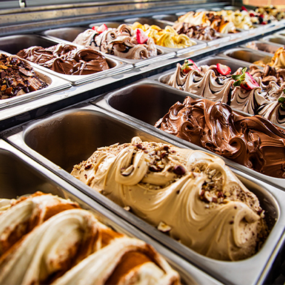 Display of various flavors of gelato or ice cream in metal containers at a shop