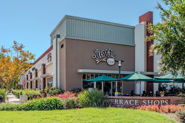 Exterior view of Lola’s Café with outdoor seating under green umbrellas